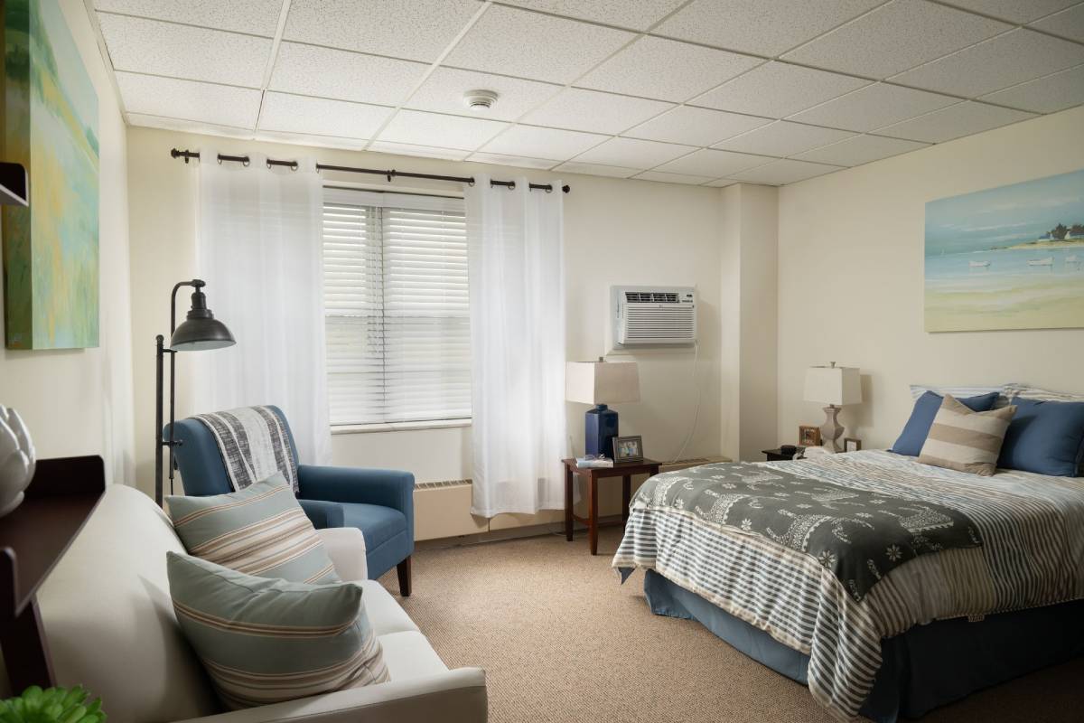Bright bedroom at Pitman Manor with twin bed, armchair and window drapes.