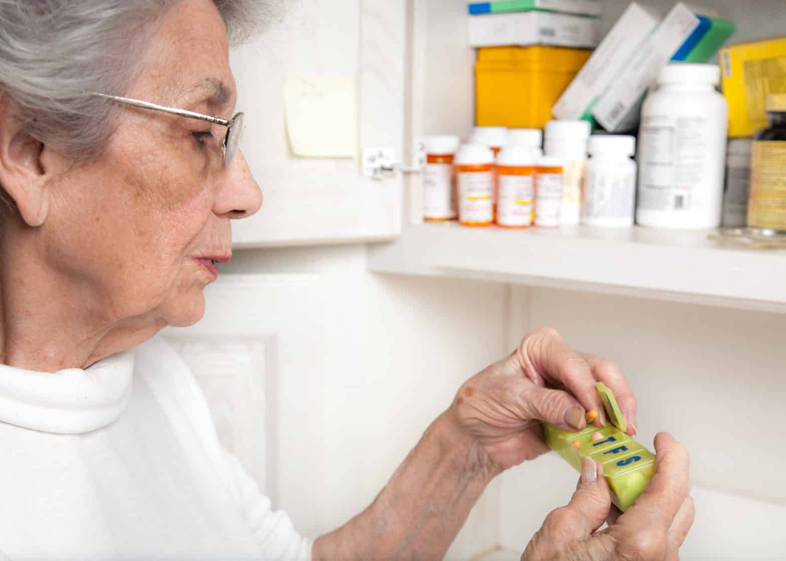 senior woman taking medicine from pill organizer