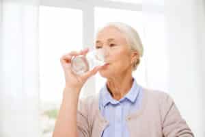 happy senior woman with glass of water at home