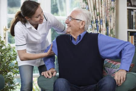 Care Worker Helping Senior Man To Get Up