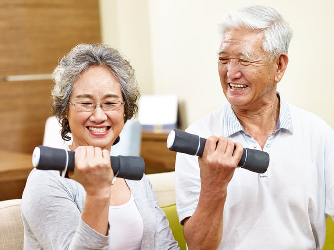 senior asian couple exercising using dumbbells
