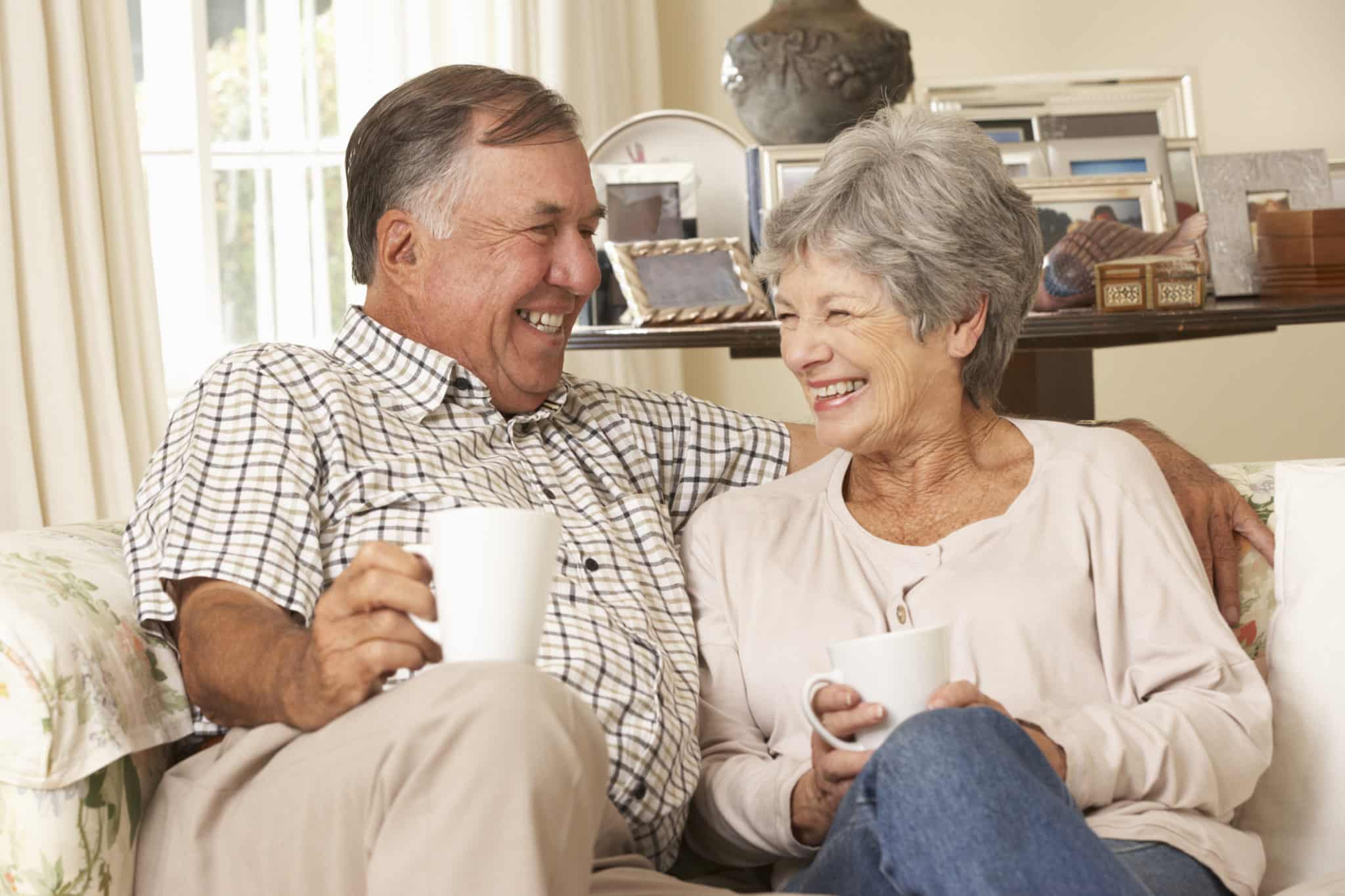 Senior Couple Sitting On Sofa Drinking Tea At Home