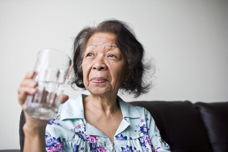 Senior black woman holding a glass of water