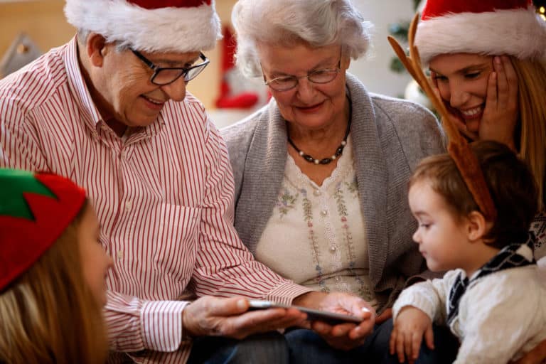 Grandparents with children looking Christmas photos on cell phone