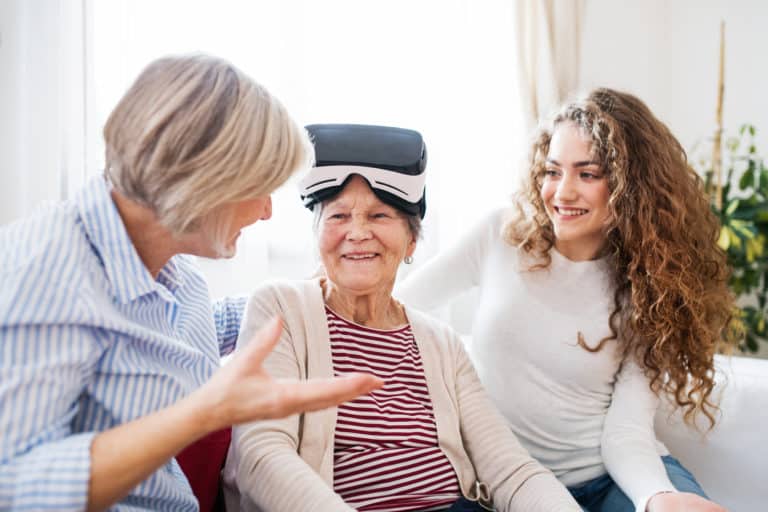 A teenage girl, mother and grandmother with VR goggles at home.