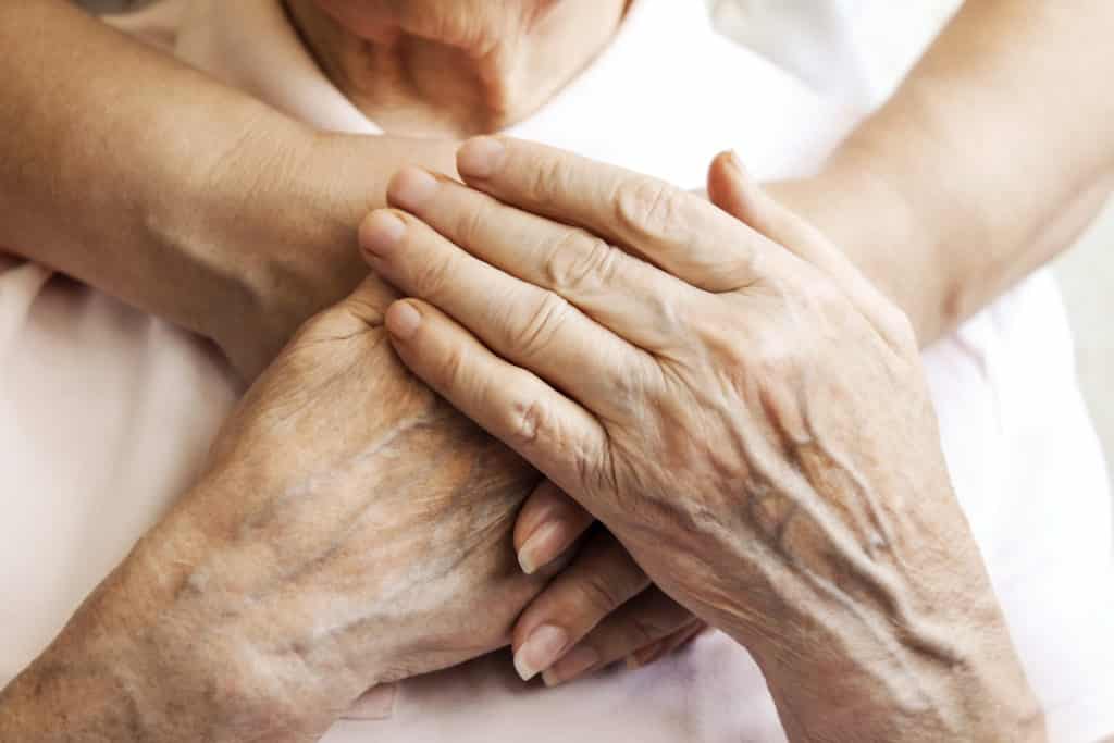 Close up of mature womans & nurse hands. Health care giving, nursing home. Parental love of grandmother. Old age related diseases.