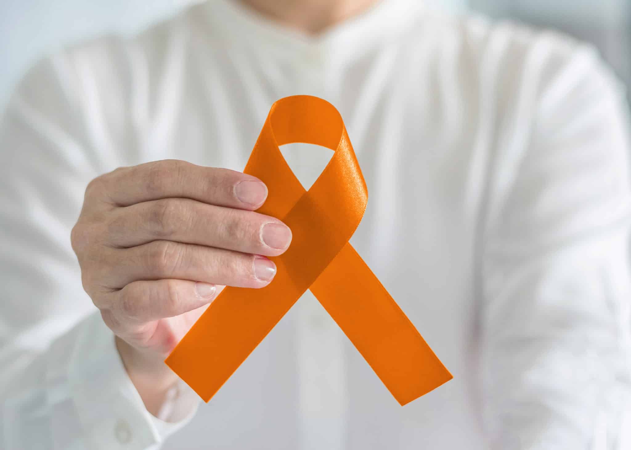 Orange ribbon for awareness on Leukemia, Kidney cancer, RDS disease, multiple sclerosis, ADHD illness, Chronic Obstructive Pulmonary Disease (COPD) in person's hand