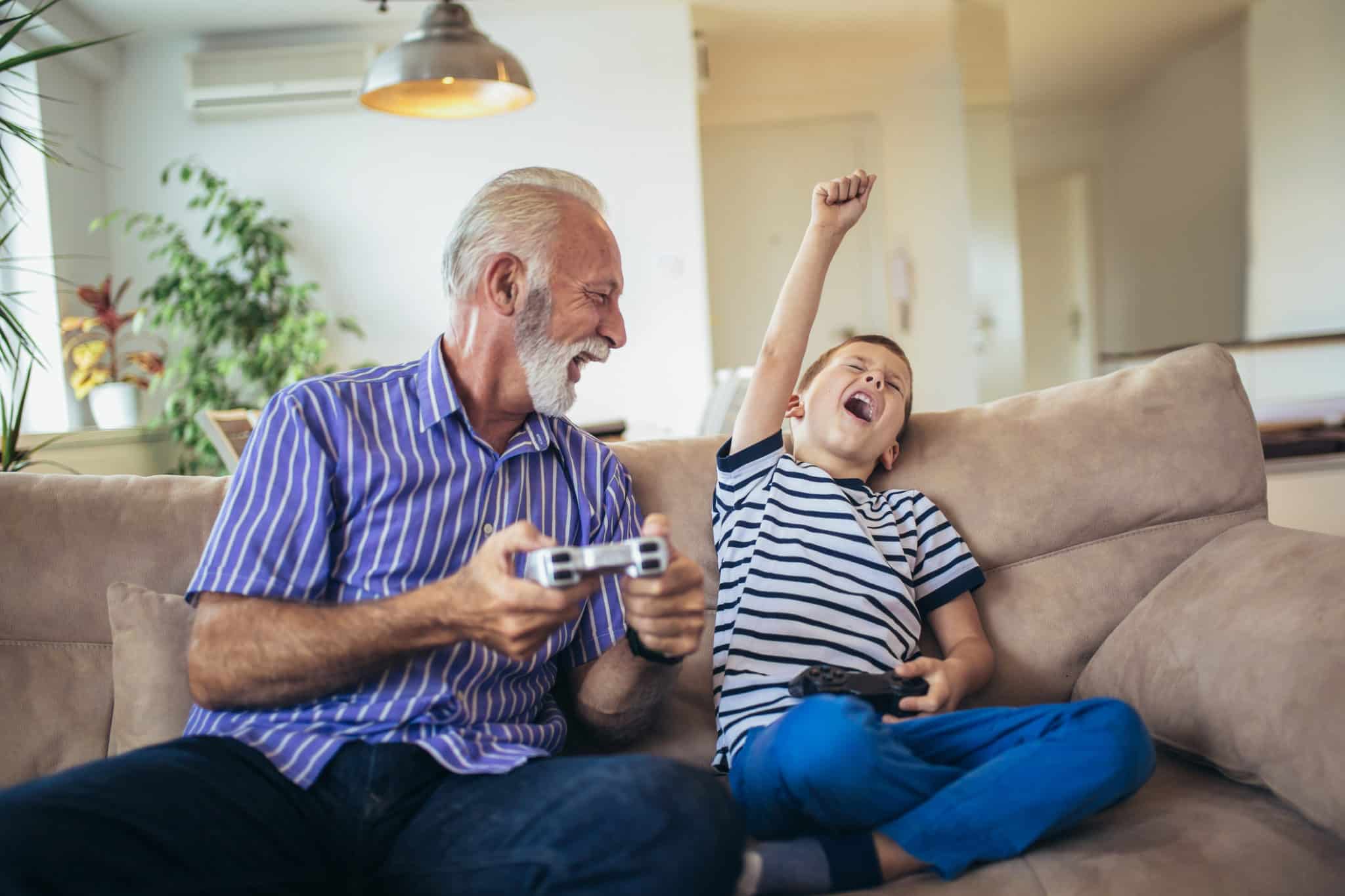 Grandfather and grandson are playing video games at home.