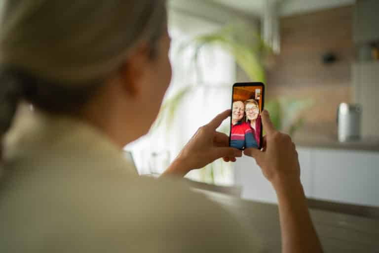 smiling senior adult parents talking with daughter over mobile phone video call