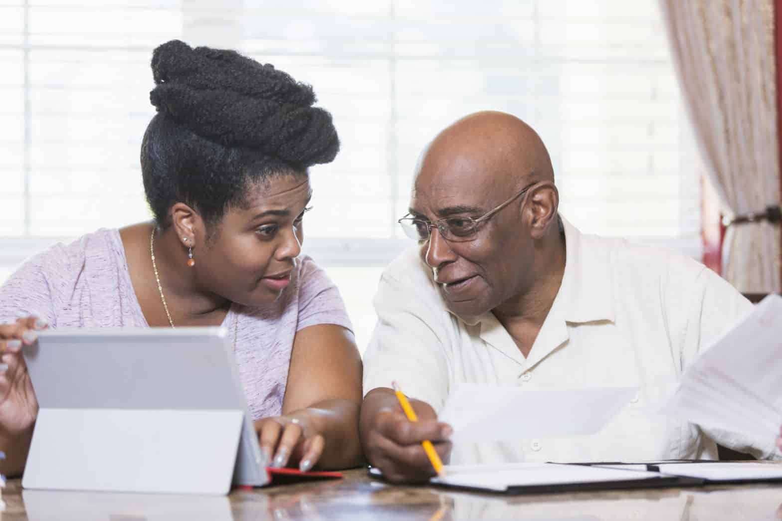 Senior man and adult daughter working on home finances