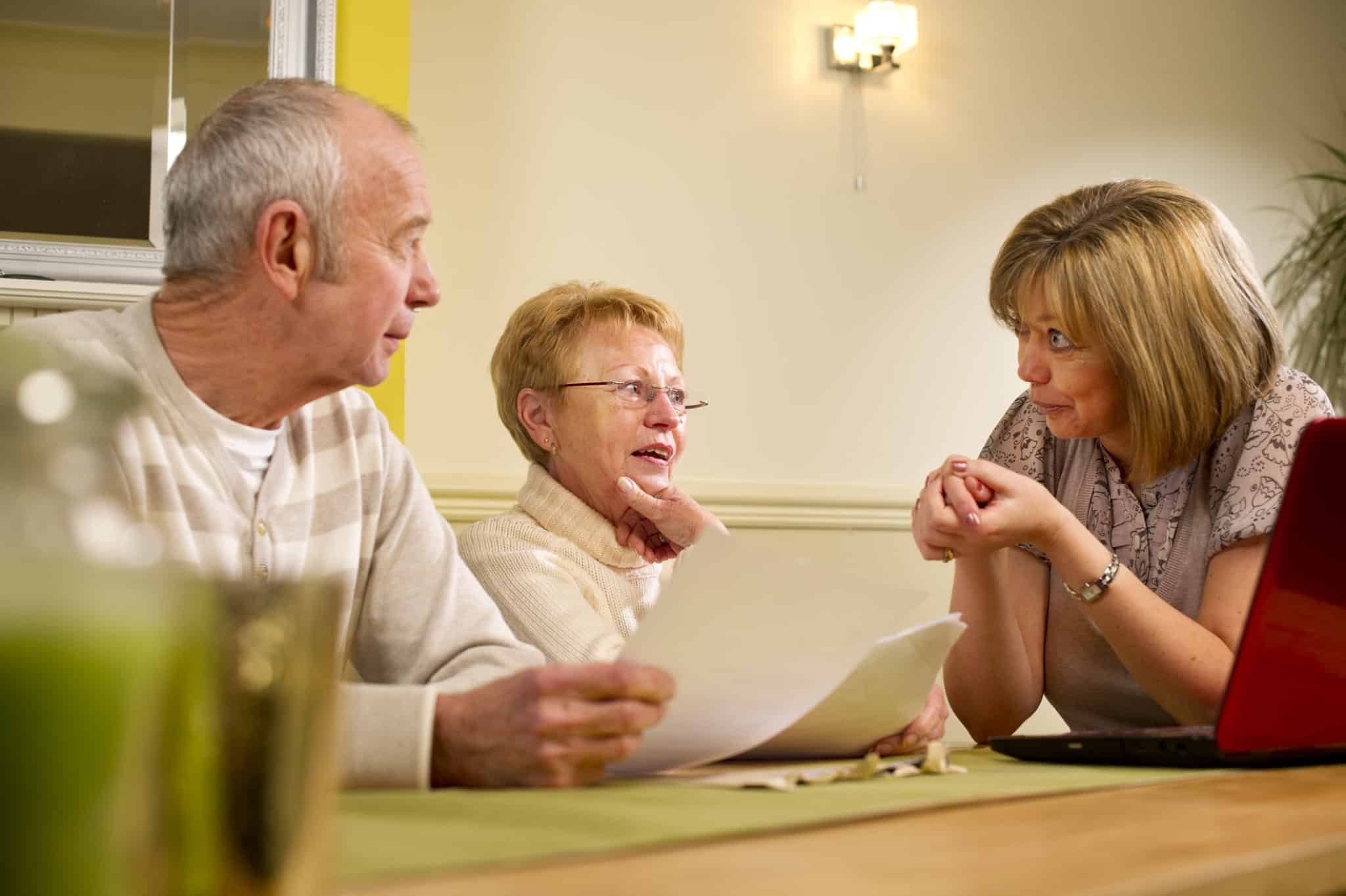 A woman discussing paperwork at a table with an older couple