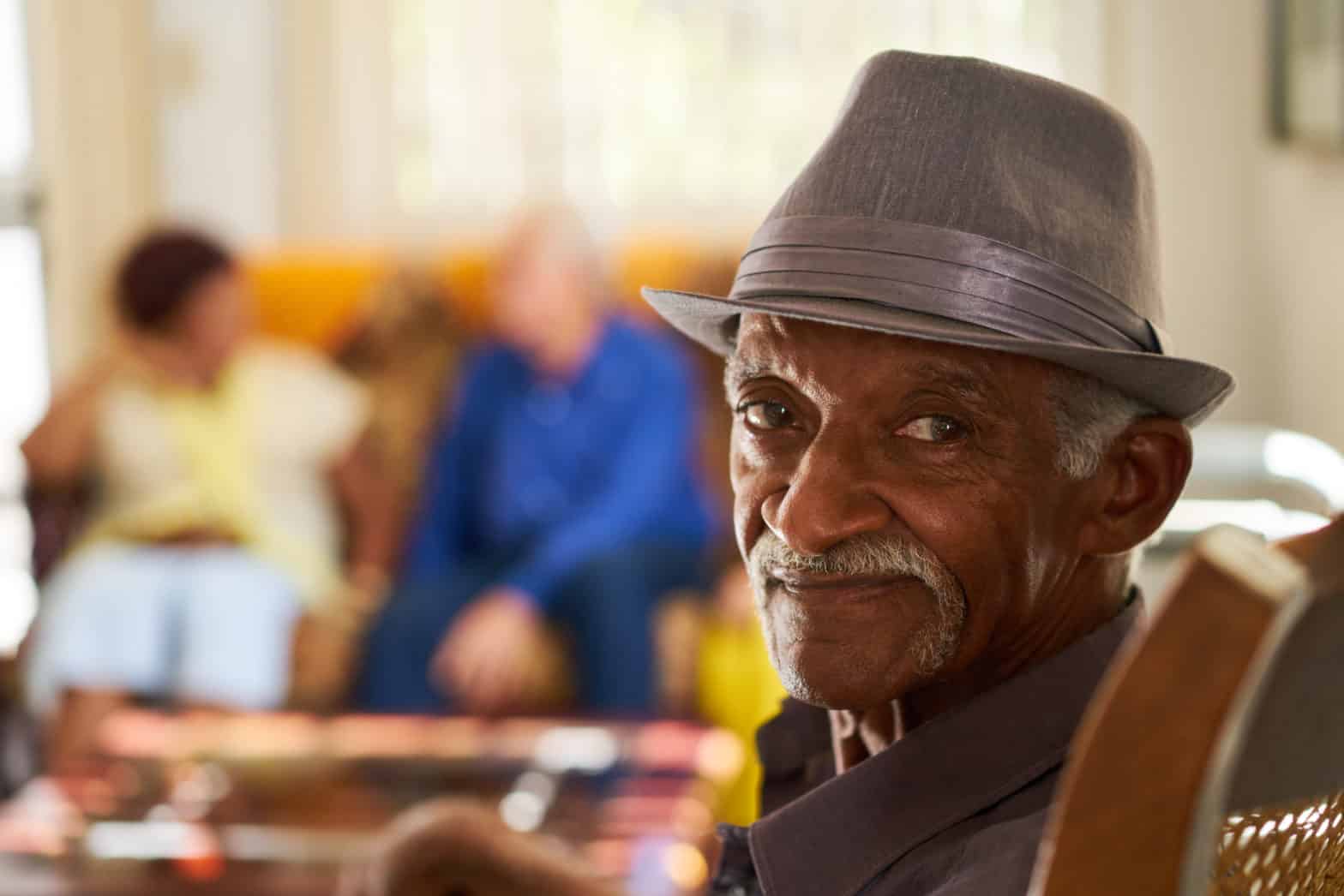 Senior Black Man With Hat Looking At Camera In Hospice