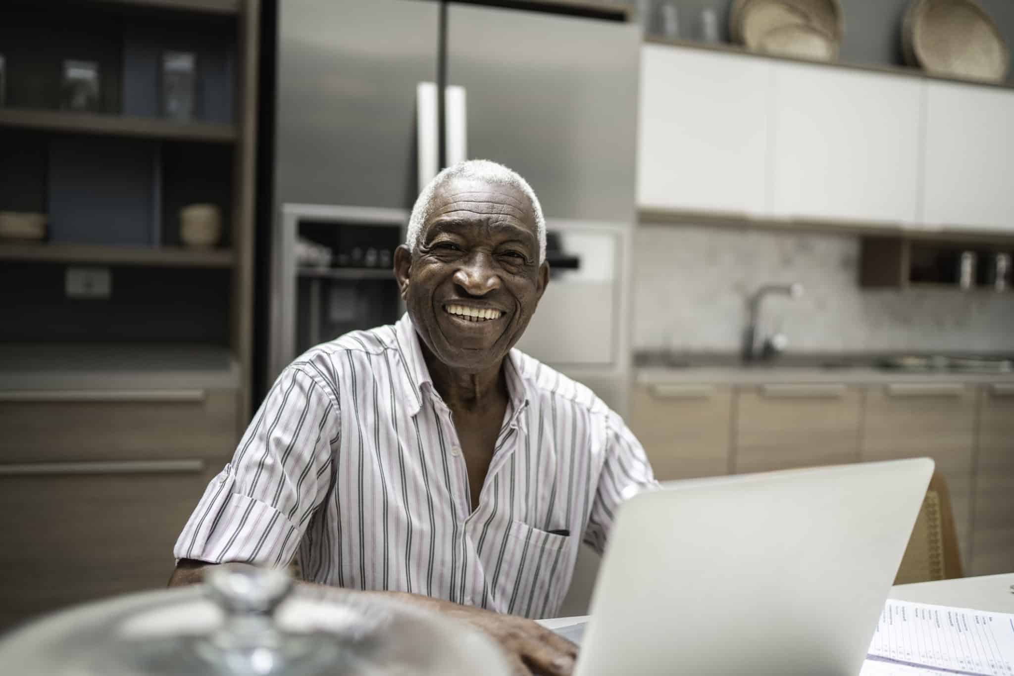 Portrait of a senior man using laptop in the kitchen table