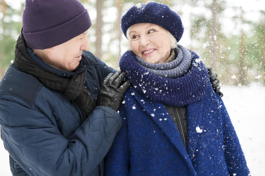 Portrait of joyful senior couple enjoying walk in winter park