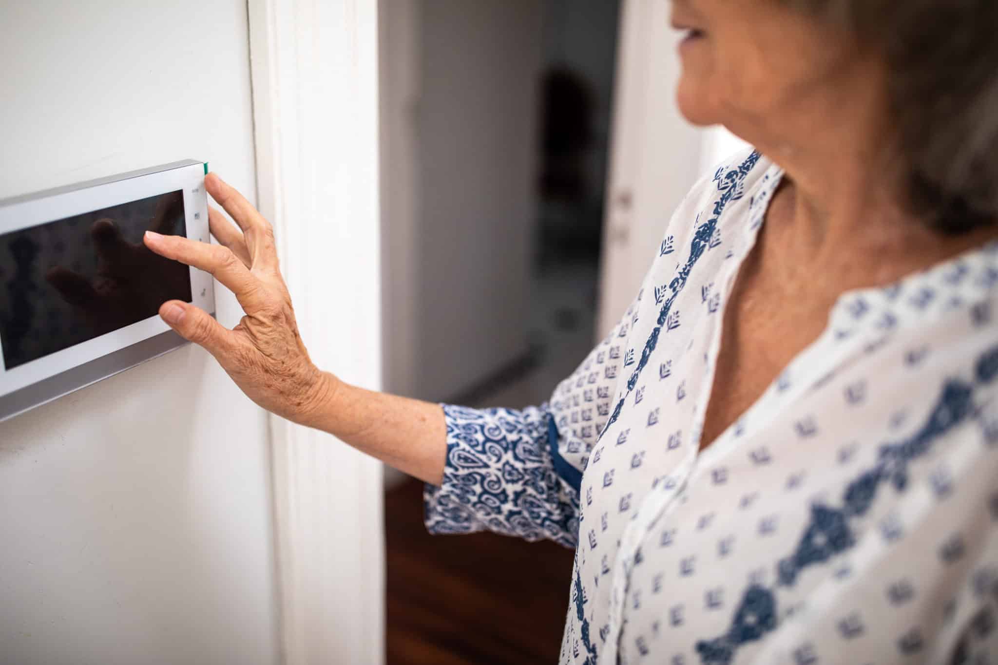 Senior woman setting burglar alarm