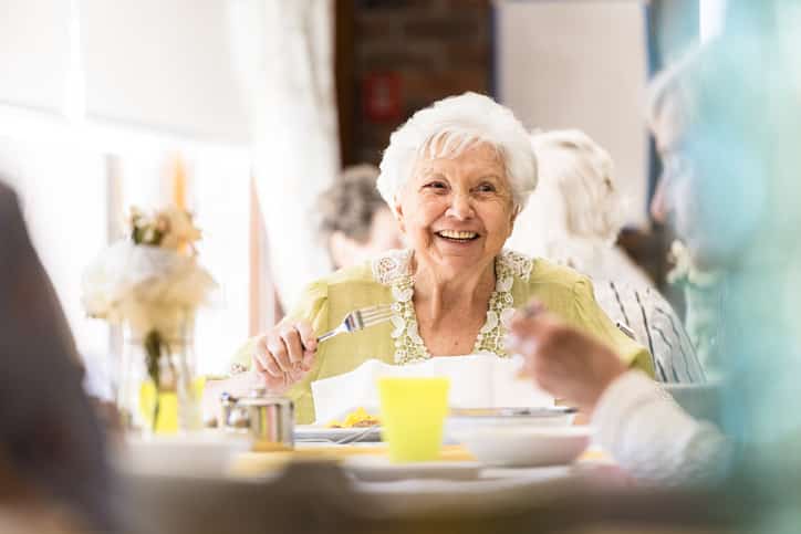 Portrait of a smiling senior woman having lunch with friends