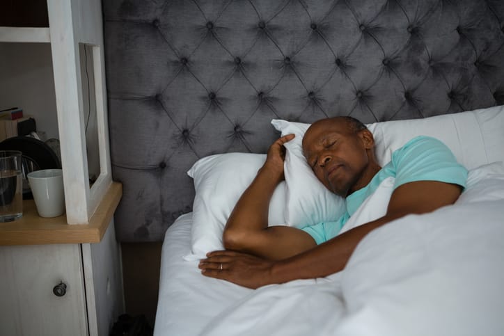 Senior man sleeping on bed at home