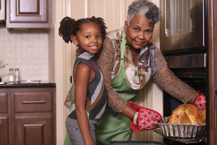 African descent family in home kitchen cooking Thanksgiving dinner.