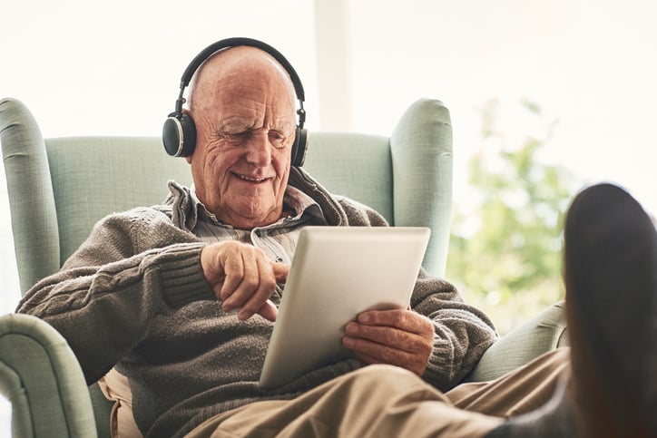 Happy elderly man at home using digital tablet