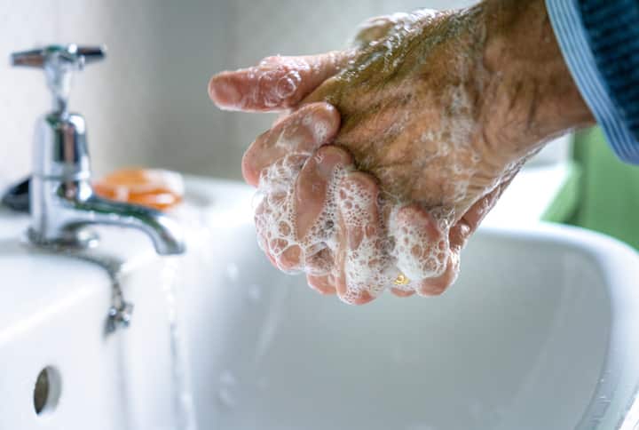 Elderly man carefully washing his hands