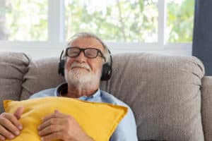 Senior retirement man listen to music using headphone feeling happy in his home